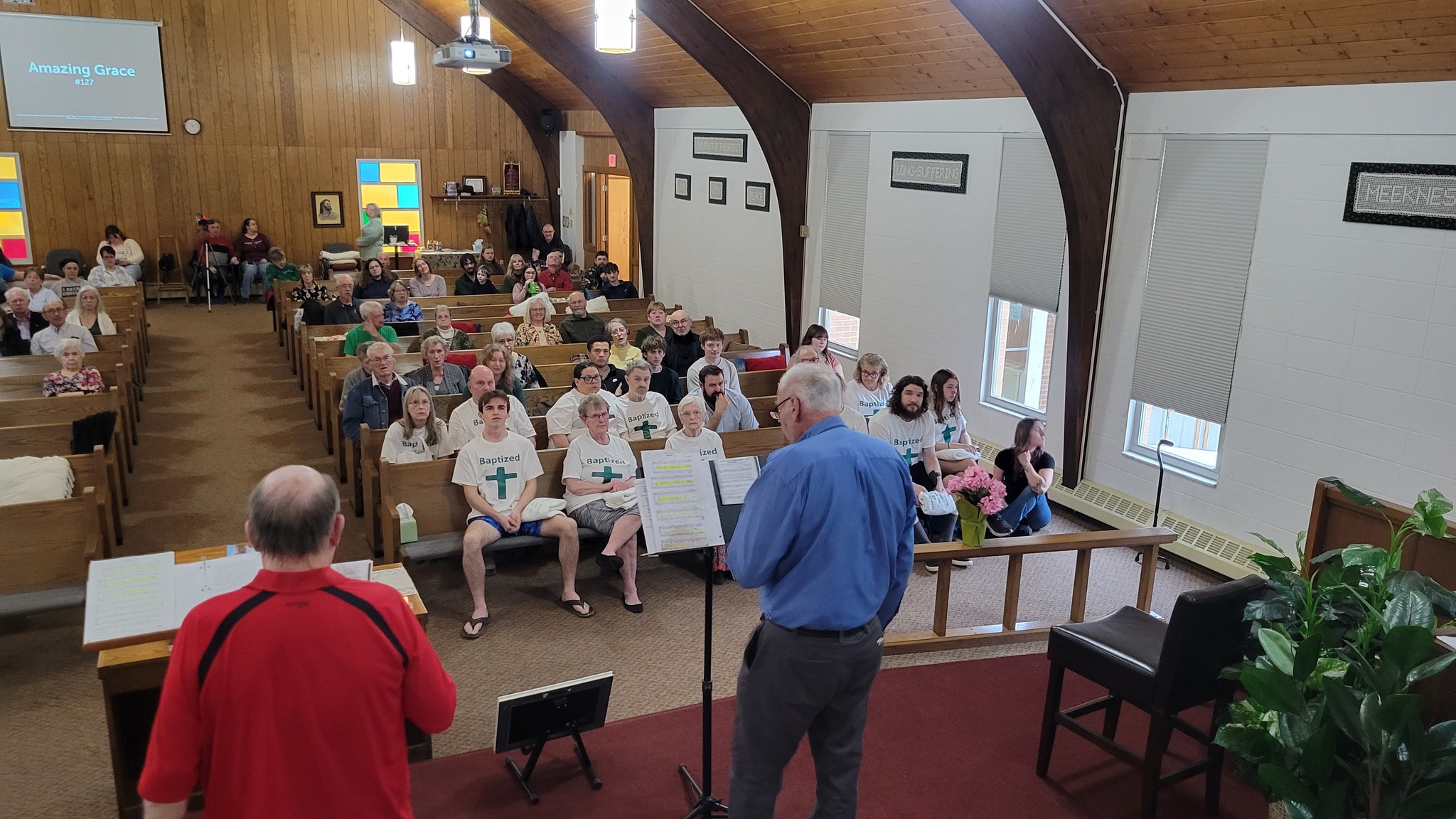 Congregation during a baptism service with Amazing Grace displayed on screen